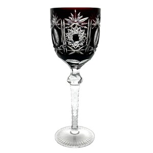 May include: A tall, clear glass wine goblet with a deep red, cut-glass bowl and a long, faceted stem. The goblet has a delicate, intricate design.