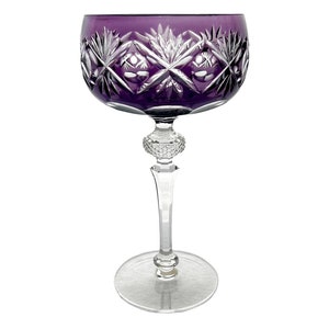 May include: A purple crystal wine glass with a cut glass design and a round knob stem.