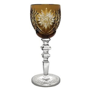 May include: A clear glass stemmed shot glass with a brown, cut-glass design. The glass has a round bowl and a tall, slender stem.