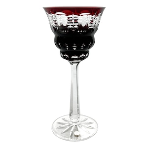 May include: A tall wine glass with a ruby red bowl and a clear, slender stem. The bowl has detailed cut glass patterns, and the base is a clear, starburst design. The glass is suitable for serving wine.