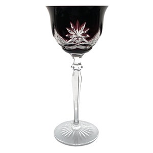 Op de afbeelding: Een wijnglas van kristal met een heldere steel en voet. De kelk is diep bordeauxrood van kleur met een sterrenpatroon. Het glas heeft een elegant, klassiek ontwerp.