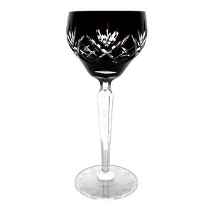 May include: A black crystal wine glass with a cut design. The glass has a long, thin stem and a round base.