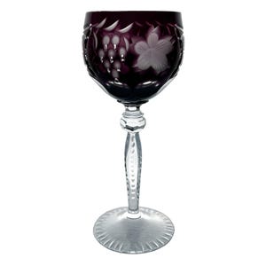 May include: A single wine glass with a deep purple bowl and a clear, faceted stem and base. The bowl features etched grape and leaf designs. The glass is designed for wine and is set against a white background.