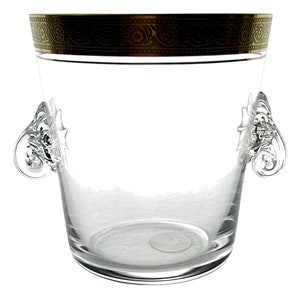 Puede incluir: Un cubo de hielo de vidrio transparente con un borde dorado alrededor de la parte superior y dos asas ornamentadas.