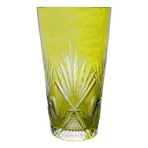 May include: A tall, chartreuse-colored glass with a cut-glass design. The glass features a pattern of vertical lines and diamond shapes, creating a textured appearance. The glass is ideal for serving beverages.