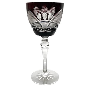 May include: A clear wine glass with a deep red, cut-glass bowl and a clear stem. The bowl has a decorative, cut-glass pattern.