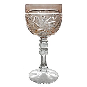 Puede incluir: Una copa de vino de cristal transparente con un diseño de cristal tallado. La copa tiene un borde rosa y un tallo grueso de cristal tallado.