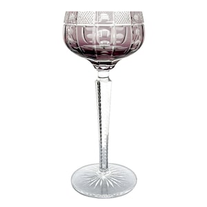 May include: A clear crystal wine glass with a long stem and a round base. The bowl of the glass is a deep purple color and features a cut pattern. The stem is clear and has a textured design. The base is clear with a starburst pattern.