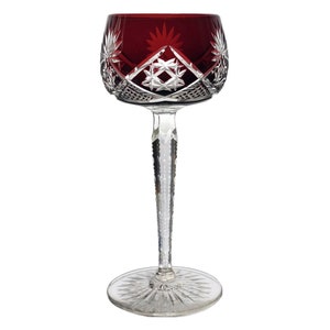 Op de afbeelding: Een robijnrood kristallen wijnglas met ingewikkelde patronen van sterren en geometrische vormen. De kelk is dieprood, de steel en voet zijn van helder kristal. De steel is lang en slank, de voet breed en stabiel.