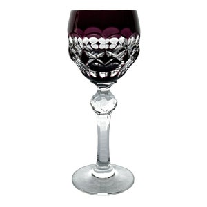 May include: A clear glass stemmed shot glass with a deep purple hue and intricate cut glass design.