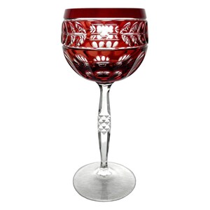 May include: A red wine glass with a clear stem and base. The bowl of the glass has a detailed, cut pattern. The rim of the glass is a solid, deep red. The stem has a decorative, geometric design.