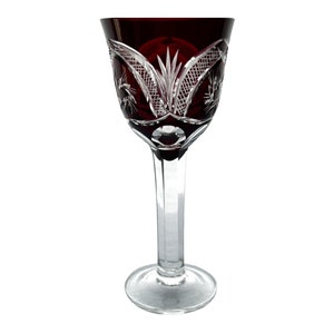 May include: A clear glass stemmed wine glass with a deep red colored bowl. The bowl has a cut glass design with a floral pattern.
