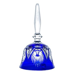 May include: A clear glass bell with a long, textured handle and a deep blue base. The bell features intricate cut glass designs, creating a decorative and elegant appearance. The bell is designed to be rung.