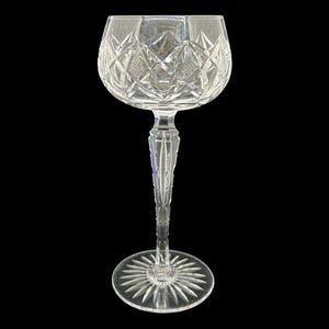 Puede incluir: Una copa de vino de cristal transparente con un diseño de cristal tallado. La copa tiene un tallo alto y una copa ancha.