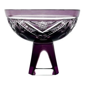May include: A purple crystal glass bowl with a starburst design and a pedestal base. The bowl has a wide rim and intricate cut patterns. The base is a geometric shape, adding a modern touch to the classic design.