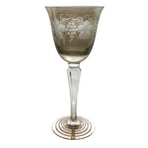 May include: A clear glass wine glass with a brown tint and an etched design of grapes and leaves.