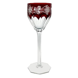 Könnte beinhalten: Ein klares Weinglas mit rubinrotem Rand und floralem Ätzdesign. Das Glas hat einen langen Stiel und einen sechseckigen Fuß. Das geätzte Design zeigt weiße Blumen und Blätter. Das Glas ist wahrscheinlich aus Kristall.