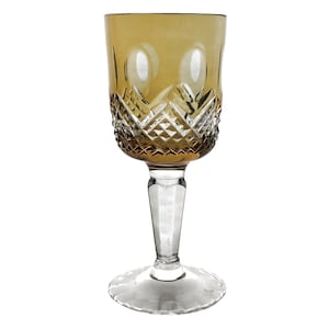 May include: A clear glass wine goblet with a cut glass design. The bowl of the goblet is amber colored.