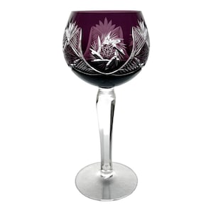 May include: A clear glass wine goblet with a deep purple hue and intricate cut glass designs. The goblet has a long stem and a round bowl.