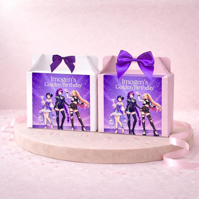 May include: Two rectangular gift boxes with handles, one white and one light pink, each topped with a purple satin bow. The front of each box features a graphic of three anime-style characters and the text Imogen's Golden Birthday in white.