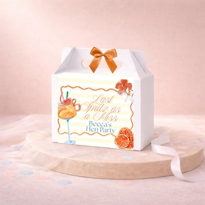 May include: White gift box with a handle and an orange bow. The box features a watercolor design with the text "Last Spritz as a Miss Becca's Hen Party", an orange cocktail, and orange slices. Perfect for a bachelorette party.