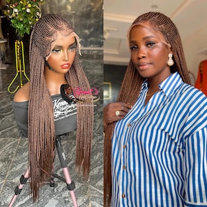 May include: A brown braided wig with a lace front is displayed on a mannequin and worn by a person. The wig features a detailed braid pattern and a natural-looking hairline. The person is wearing a blue and white striped shirt.