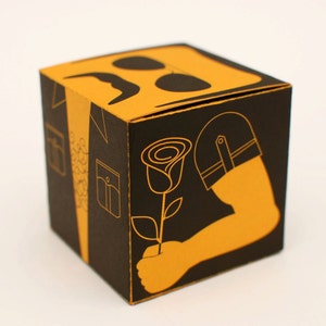 May include: A black and yellow gift box with a rose, a mustache, and a stylized arm with a hat on it.