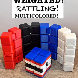May include: A collection of multicolored, weighted, and rattling fidget toys. The toys are in red, black, blue, and white. The text on the top of the image reads: WEIGHTED! RATTLING! MULTICOLORED!