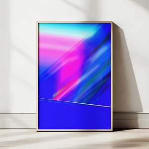 Op de afbeelding: Abstracte kunstafdruk in een houten lijst. Het kunstwerk toont een levendige mix van kleuren, waaronder blauw, roze en turquoise, met dynamische penseelstreken. Het onderste deel van de print is effen diepblauw.