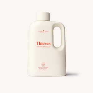 May include: Off-white laundry detergent bottle with a handle. The word "Thieves" is in red, with "Laundry Detergent" below it. The bottle also has the Young Living logo and text indicating it's made with essential oils.