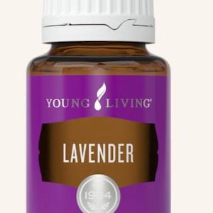 Może przedstawiać: Brązowa szklana butelka olejku eterycznego Young Living Lavender. Butelka ma białą nakrętkę i fioletową etykietę z napisem "LAVENDER". Etykieta zawiera również tekst "PREMIUM ESSENTIAL OIL" i "15 ml".