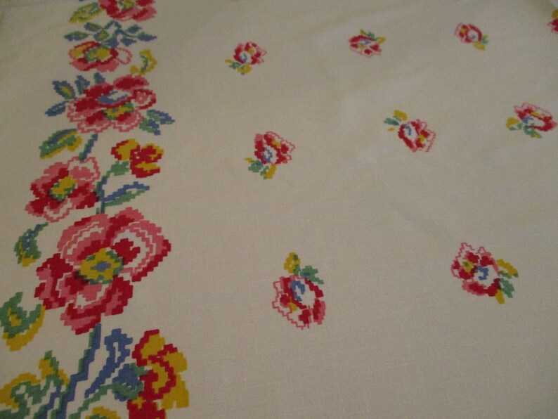 Pu&ograve; includere: Tessuto color crema con un motivo floreale ripetuto. I fiori sono resi in uno stile pixelato, con sfumature di rosso, rosa, giallo, blu e verde. Un bordo di fiori corre lungo il lato sinistro.