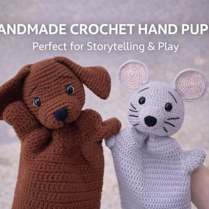 May include: Handmade crochet hand puppets of a brown dog and a grey mouse. The dog has floppy ears and a black nose. The mouse has large ears and whiskers. The text "HANDMADE CROCHET HAND PUPPET" is at the top of the image.