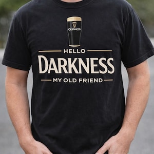 May include: Black t-shirt featuring a Guinness pint glass graphic above the words "HELLO DARKNESS MY OLD FRIEND" in a bold, cream-colored font. The shirt is a classic crew neck style.