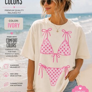 Könnte beinhalten: Ein elfenbeinfarbenes, kurzärmeliges Oversize-T-Shirt mit einem Grafikdruck eines rosafarbenen Bikinis mit weißen Punkten. Das Shirt besteht aus ringgesponnener Baumwolle und hat eine lockere Passform. Der Text Comfort Colors ist aufgedruckt.