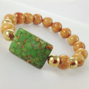 May include: A green and brown stone bracelet with gold accents. The bracelet is made of round beads and a rectangular green stone.