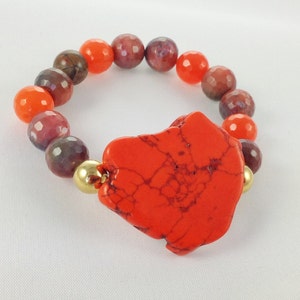 May include: A bright orange and purple beaded bracelet with a large, bright orange, freeform stone charm.