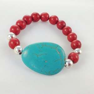 May include: A turquoise stone bracelet with red and silver beads. The turquoise stone is oval shaped and has a marbled pattern.