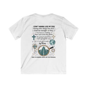May include: White t-shirt with a graphic design on the back. The design includes text, crosses, a road, and a globe. The text reads "I DON'T WANNA LOSE MY SOUL" and other related phrases. The shirt is a casual wear item.