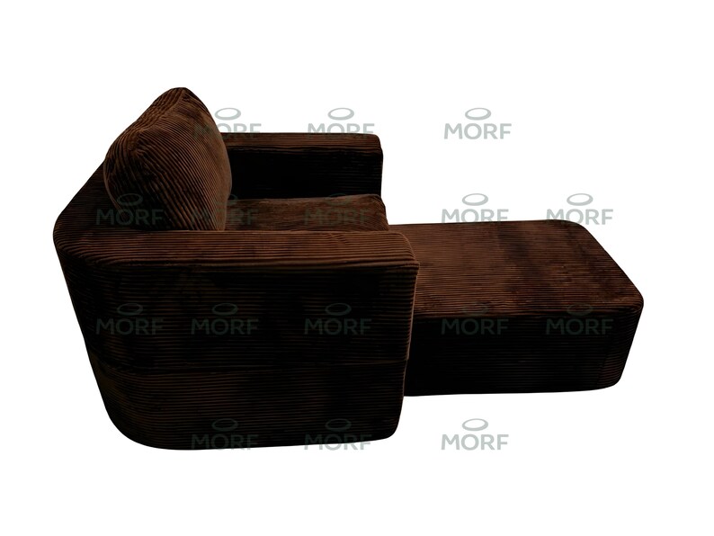 K&ouml;nnte beinhalten: Ein braunes Cord-Ecksofa mit angebauter Ottomane. Das Sofa hat ein abgerundetes Design mit einem dicken, strukturierten Stoff. Die Ottomane ist rechteckig und passt farblich und materialm&auml;&szlig;ig zum Sofa. Das Sofa steht vor wei&szlig;em Hintergrund.