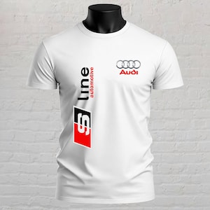 Op de afbeelding: Een wit T-shirt met korte mouwen voorzien van het Audi-logo in zilver en rood op de rechterborst. Een verticale afbeelding aan de linkerkant toont de tekst S line automotive in zwart en rood, met een groot rood en zwart S line embleem.