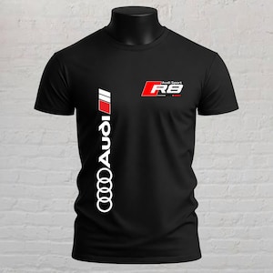 May include: A black short-sleeved t-shirt featuring a vertical white Audi logo with a red accent stripe on the left side. The upper right chest displays a red and white Audi Sport R8 logo. The shirt has a crew neckline and a standard fit.