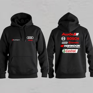 Op de afbeelding: Een zwarte hoodie met het Audi Sport-logo en de Audi-ringen op de voorzijde. De achterkant toont een verzameling logo's van automerken, waaronder Audi, Bosch, BBS, Brembo, Hankook en Castrol in de kleuren wit, rood en groen.