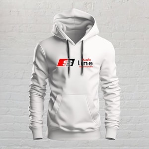 Peut inclure: Un sweat-shirt à capuche blanc à manches longues avec une poche kangourou sur le devant et des cordons de serrage noirs. La poitrine présente un carré rouge avec un S blanc, suivi du texte noir Audi line automotive imprimé devant.