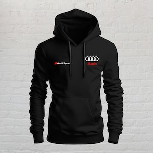 Può includere: Una felpa nera con cappuccio, maniche lunghe, tasca frontale a marsupio e coulisse regolabili. Il petto presenta il logo bianco Audi Sport a sinistra e l'emblema bianco dei quattro anelli Audi con la scritta rossa Audi a destra.