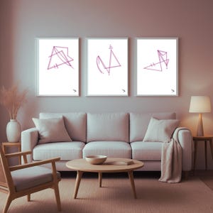 Op de afbeelding: Drie ingelijste abstracte kunstprints met geometrische vormen in paarse tinten. De prints worden weergegeven boven een lichtgekleurde bank in een woonkamer. De kamer heeft een neutraal kleurenpalet met een houten salontafel en een lamp.