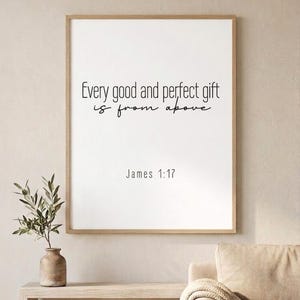 Può includere: Stampa incorniciata con il testo "Every good and perfect gift is from above" e "James 1:17" in corsivo nero. La stampa è in una cornice di legno chiaro, esposta su un tavolo di legno chiaro con un vaso e una pianta.