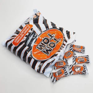 May include: A bag of Tom Tom strong menthol flavored candy with a black and white striped design and an orange oval logo. Several individually wrapped candies are scattered around the bag.