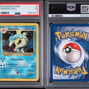 May include: A graded 1999 Pok&eacute;mon Game Gyarados-Holo card. The front of the card features a blue and yellow design with a Gyarados illustration and text. The back has a blue background with the Pok&eacute;mon logo and a Pok&eacute; Ball.