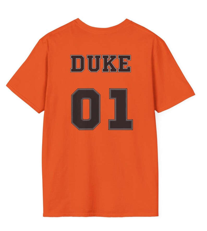 May include: A bright orange short-sleeved t-shirt featuring the word DUKE in black block letters above the large black number 01. The text and number are centered on the back of the shirt, displaying a bold, high-contrast design.